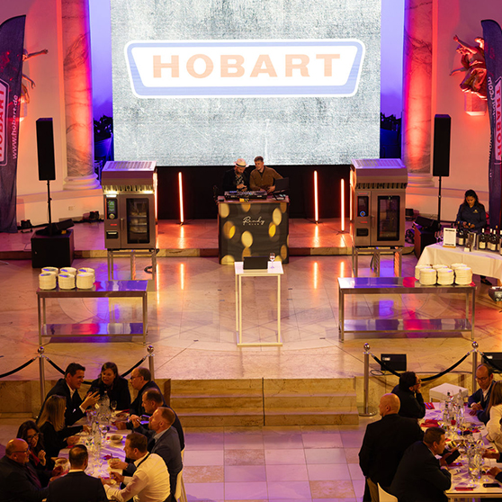 HOBART event featuring a stage, kitchen appliances, and guests in a festive setting
