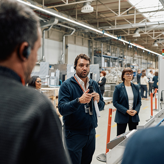 Group of people attending a site visit in an industrial setting with machinery in the background
