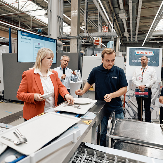 Presentation of a HOBART system with participants at a conveyor belt in an industrial setting