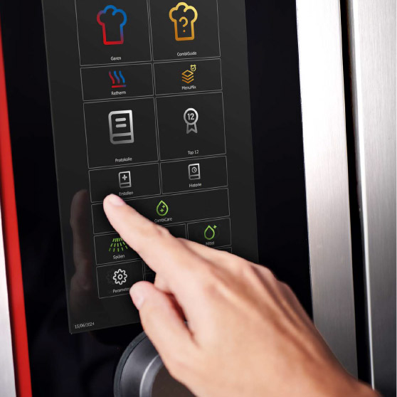 Close-up of a finger interacting with a touchscreen menu displaying various function icons such as Cooking, CombiGuide, Retherm, MenuPlus, Logs, Settings, and Cleaning.
