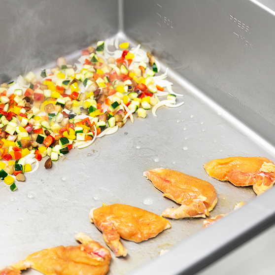 Interior of a HOBART Precipan with diced vegetables and seared poultry, multifunctional cooking technology appliance for professional kitchens.
