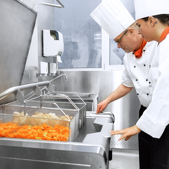 HOBART Precipan operating in a modern commercial kitchen, high-performance stainless-steel cooking system with a spacious pan, perfect for preparing vegetables such as carrots and cauliflower, designed for time and energy efficiency, precise temperature control, and easy cleaning for foodservice operations.
